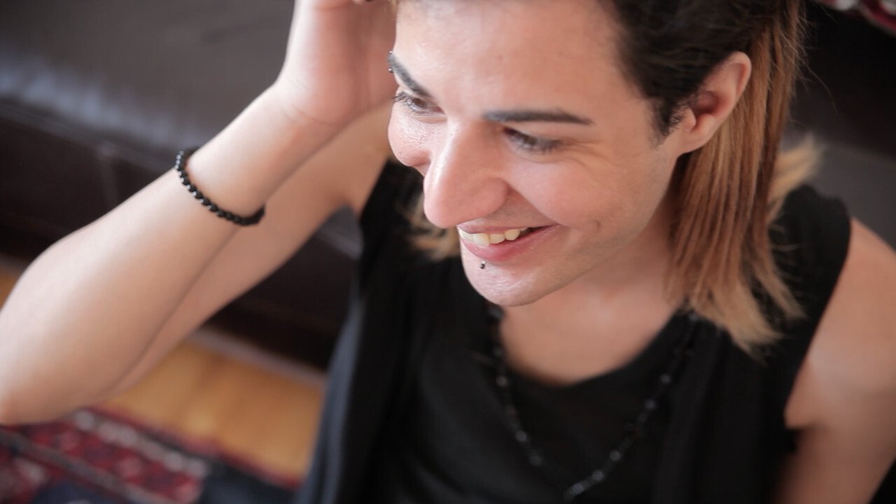 Portrait of a person tucking their hair behind their ear and smiling