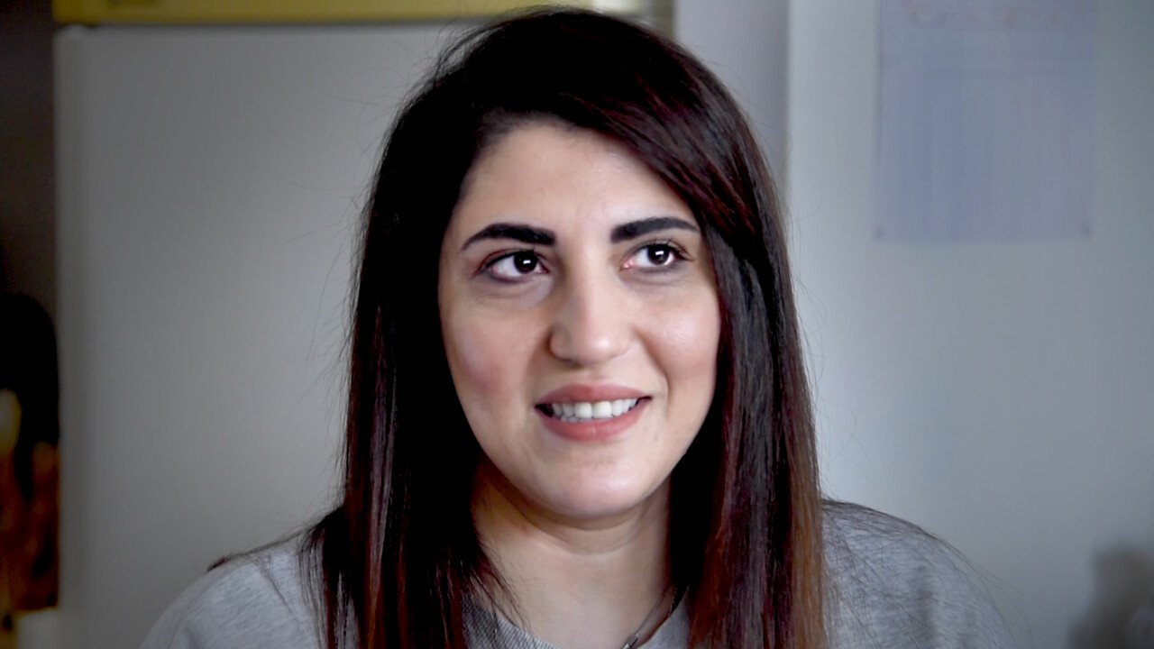 Portrait of female read person with long brown hair and brown eyes smiling and looking up and sideways.
