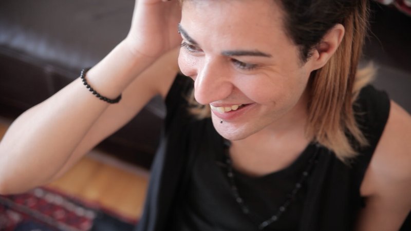 Portrait of a person tucking their hair behind their ear and smiling