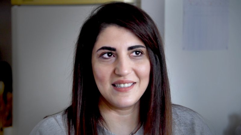 Portrait of female read person with long brown hair and brown eyes smiling and looking up and sideways.